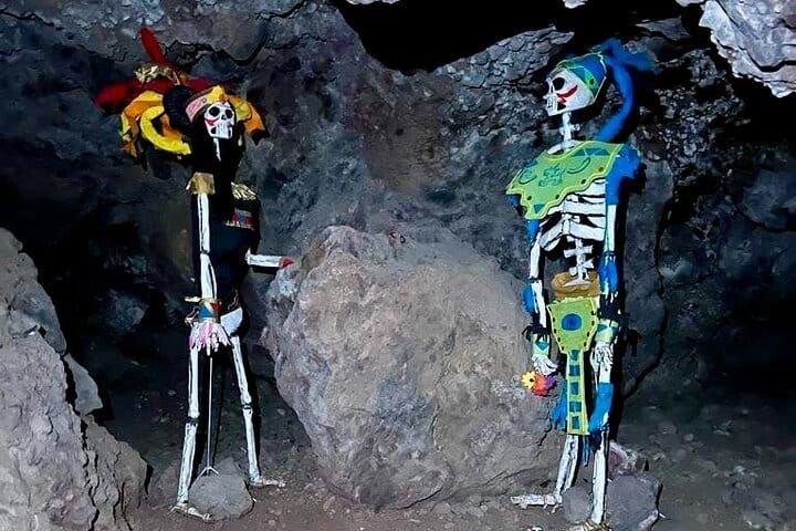 Two life-size decorated catrina figures set up inside the cave