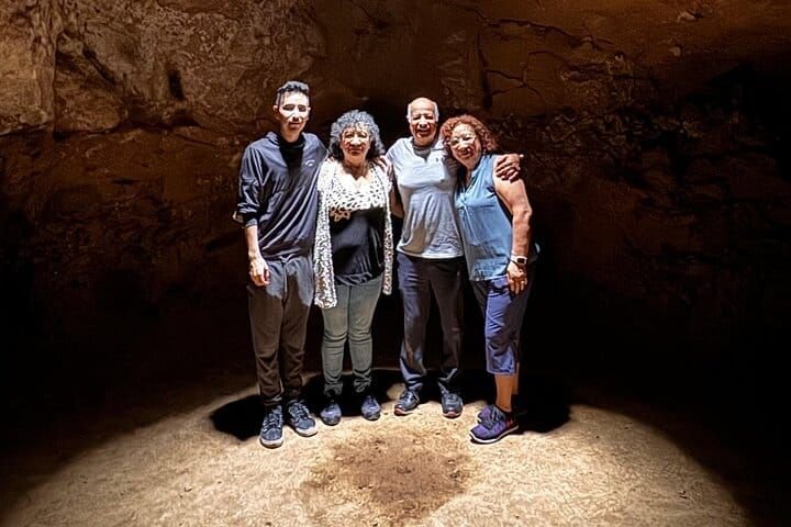 A family of four posing in the cave's shaft of light