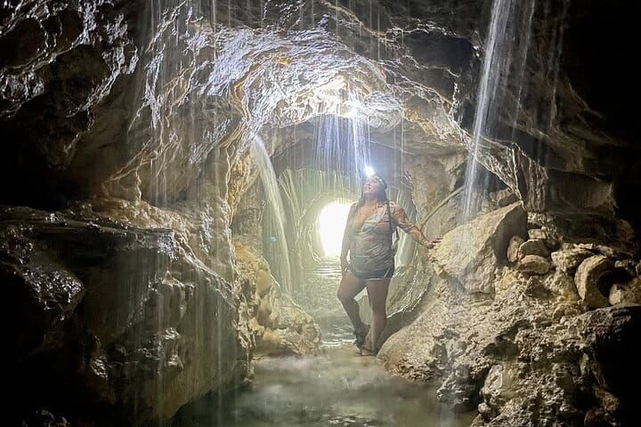 Recorriendo la gruta con lámpara de cabeza entre cortinas de agua tibia