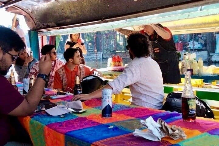 The group around the table while the mixologist pours behind them