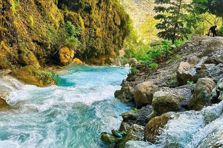El río termal turquesa corriendo entre las rocas del cañón