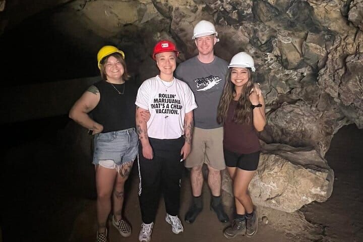 Four visitors in safety helmets inside the underground cave
