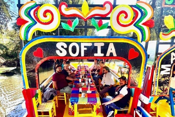 Group aboard the "Sofía" trajinera, table set under the painted arch