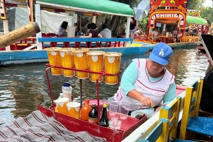 A vendor pulls her canoe alongside with tall rimmed drinks