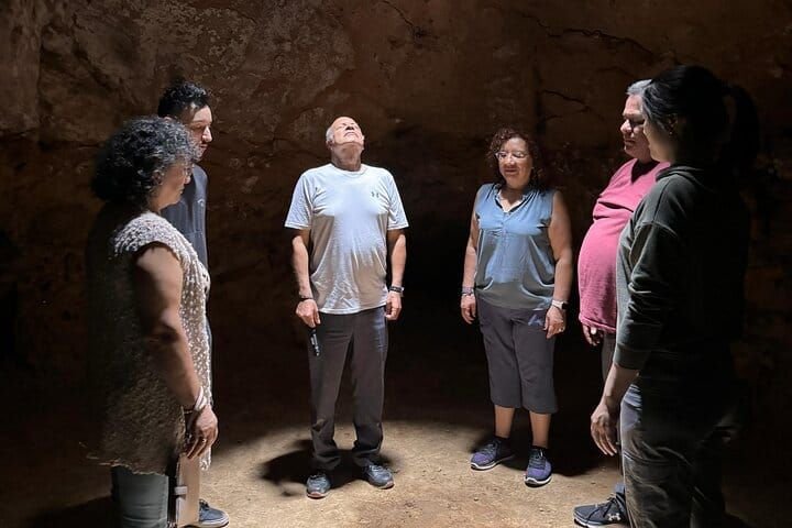 The group standing in a circle under the cave vault, listening to the guide